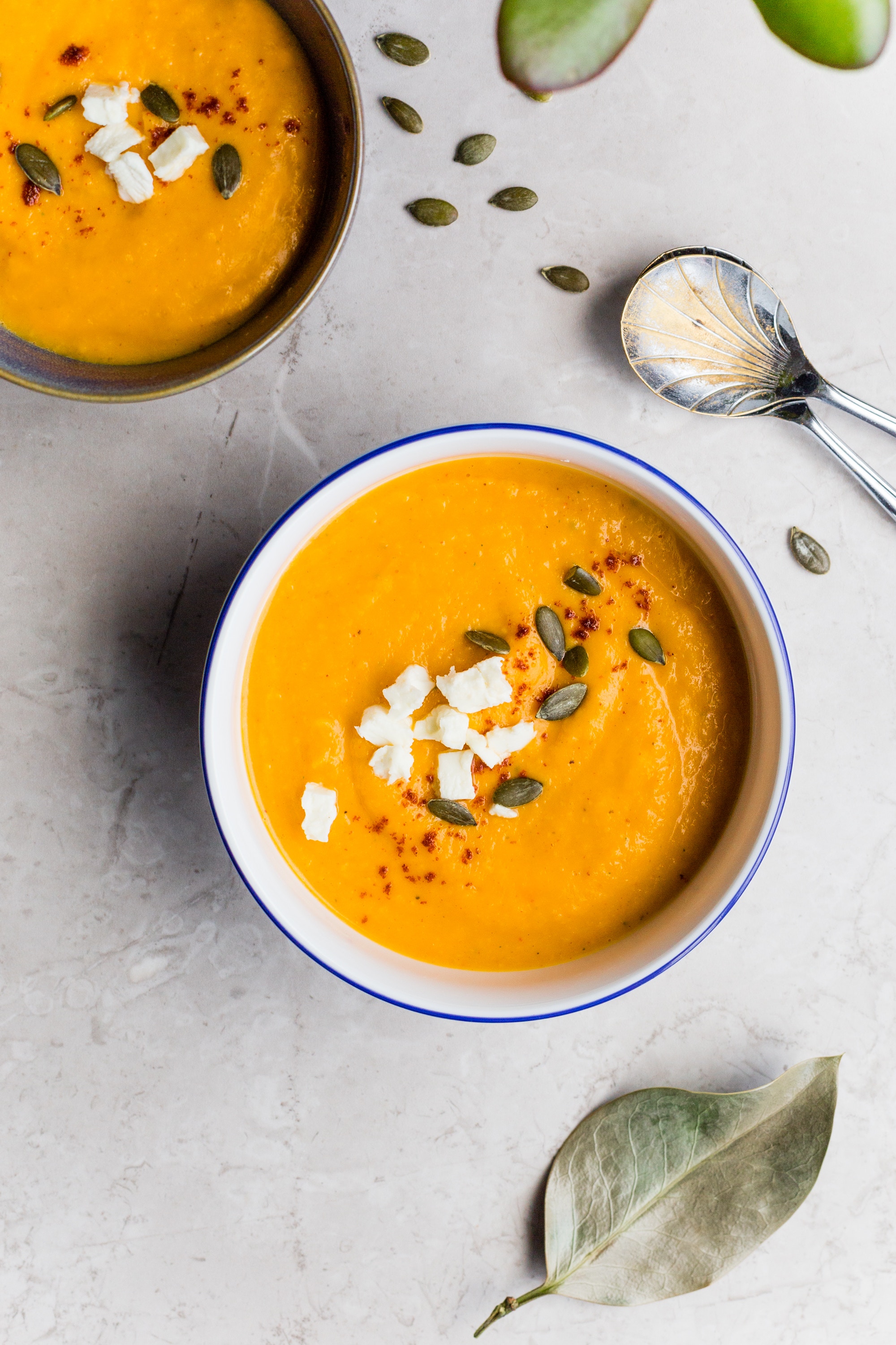 orange seasonal soup with seeds and cheese inside a brown bowl